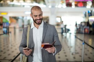 Smiling businessman holding his passport and cellphone.