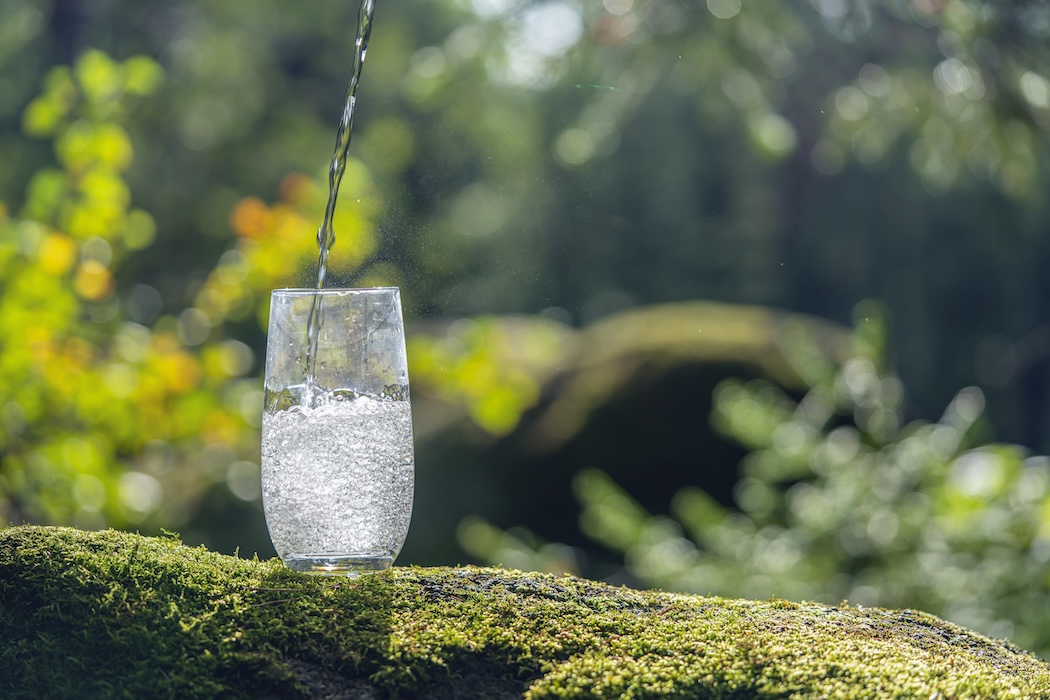 A stream of purified water pouring into a glass tumbler.