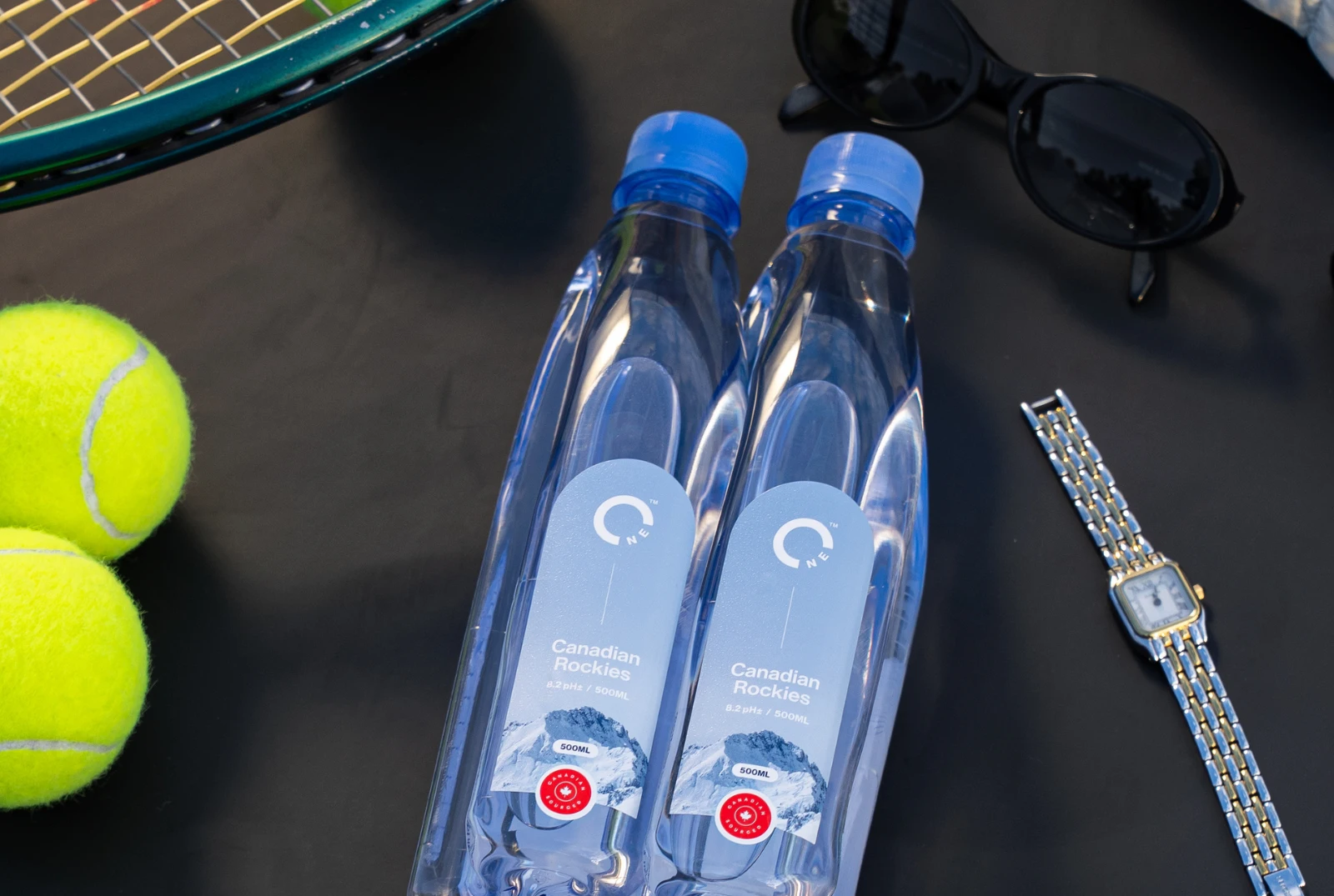 Interlocking One Water bottles surrounded by tennis equipment.