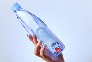 Woman's hand holding a One Water bottle against a gray backdrop.