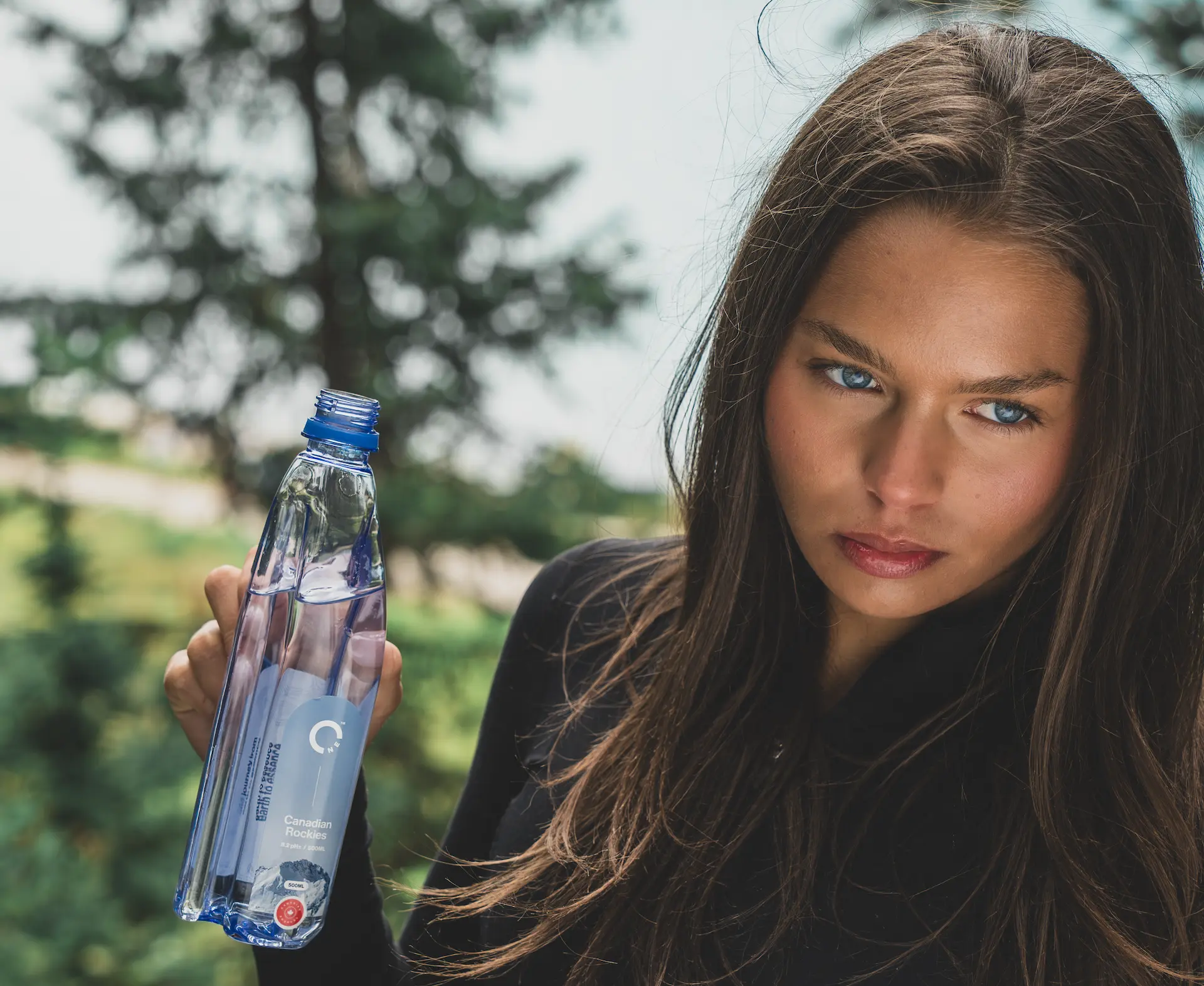 Female model holding One Water bottle at the source in Canada.
