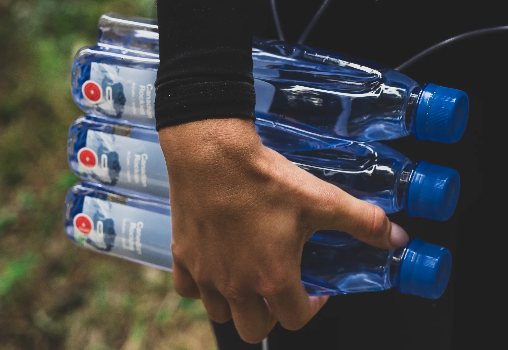 Woman holding three interlocked One Water bottles.